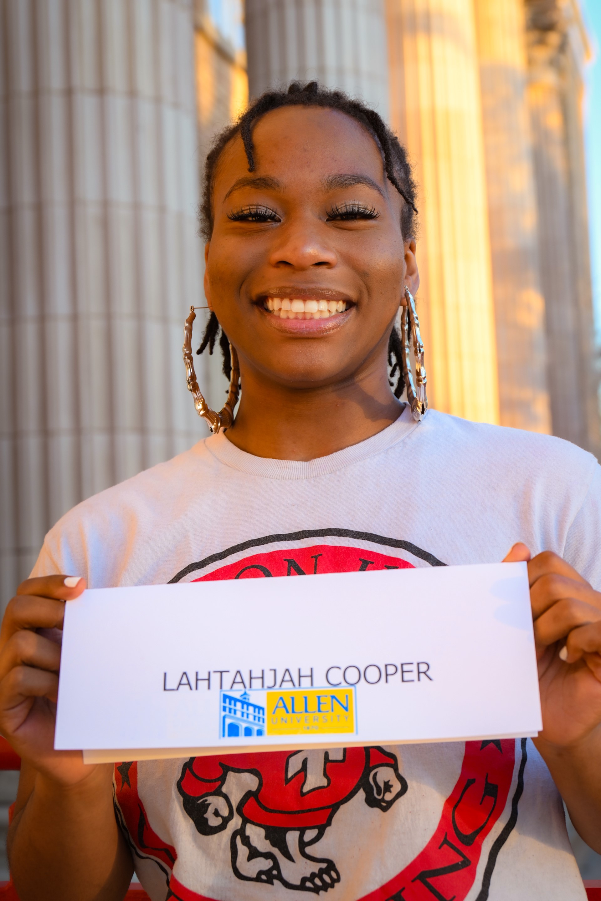 Lahtahjah Cooper smiles with her nametag showing she's signing to Allen University